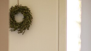 Ein Zimmer mit einem Holztisch, einer schwarzen Schreibtischlampe, einem weißen Stuhl und einem Fenster mit einem Metallgeländer.