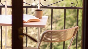 Ein Balkon mit Tisch und zwei Stühlen, auf einem Tisch ein Buch und eine Tasse.