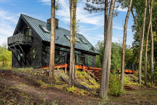 A cabin with a steep roof, wooden exterior, and a balcony. - The River House: San Miguel Sanctuary (Telluride)