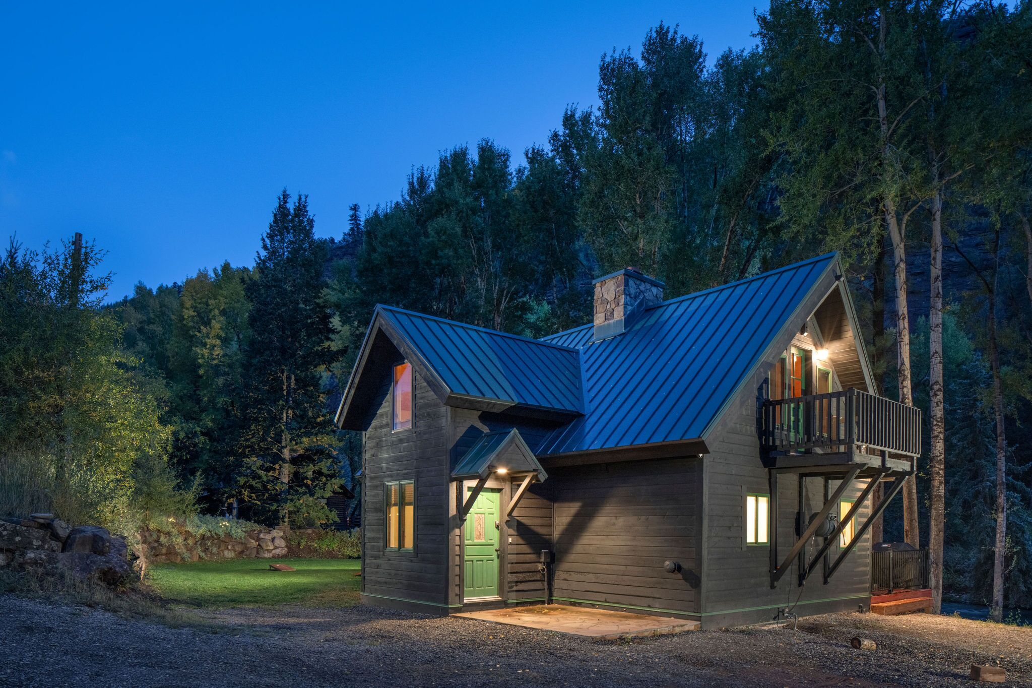 Eine Holzhütte mit Metalldach, einer grünen Tür und einem Balkon.