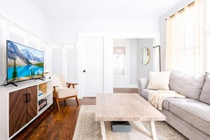 A modern living room with a flat-screen TV, a sofa, a coffee table, and a chair. - Yale Science Park 1BR | Free Parking (New Haven)