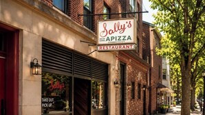 Un bâtiment en briques avec une enseigne indiquant le restaurant Sally's Apizza.