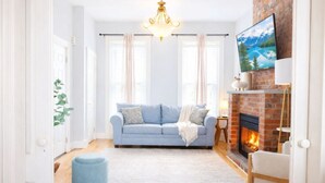 Un salon avec un canapé bleu, une cheminée et un lustre.