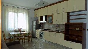 A compact kitchen with a dining area, featuring a refrigerator, oven, and cabinets. - SEA HOUSE KAMARATON (Marina di Camerota)