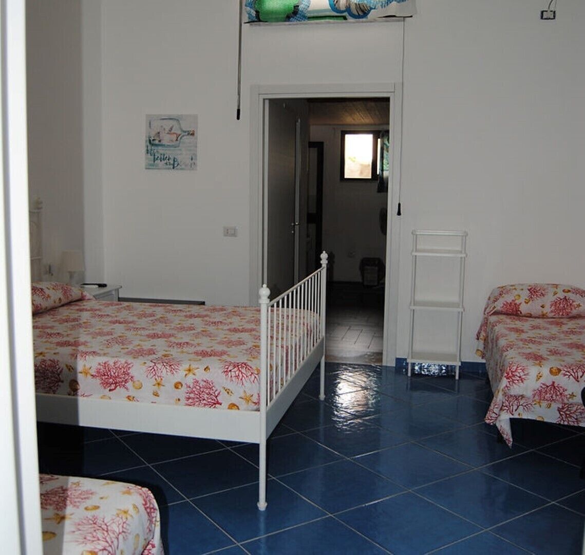 Een kamer met twee bedden, een witte deur en een betegelde vloer.
