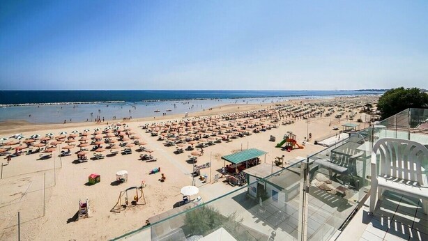 Una playa con filas de tumbonas y sombrillas, una torre de salvavidas y una vista despejada del océano.