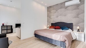 Un dormitorio moderno con una cama grande, cabecera con diseño geométrico, mesitas de noche con lámparas y un escritorio pequeño con una silla.