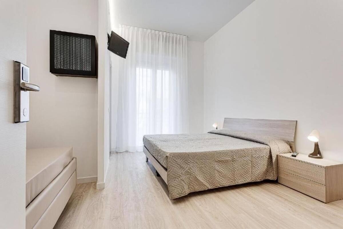 A bedroom with a bed, bedside table, and a TV mounted on the wall.