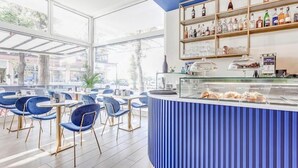 Zona de bar moderna con sillas azules, una barra con vitrina y estanterías llenas de botellas.
