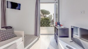 Una sala de estar moderna con un sofá, un televisor de pantalla plana y un ventanal corredero que da a un balcón.