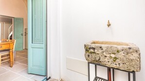 Un baño con lavamanos de piedra, una puerta y piso de baldosas.