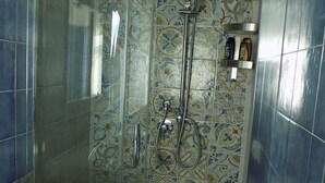 Une douche avec une porte en verre et un mur carrelé orné d’un motif floral.