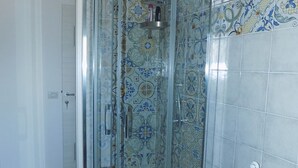 Une douche avec des carreaux décorés et une porte en verre.