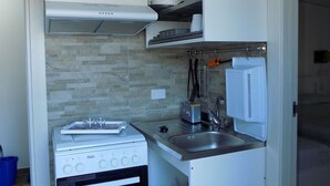 Une cuisine de taille réduite, équipée d’une cuisinière, d’un évier et d’un petit plan de travail.