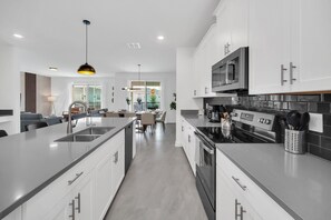 A modern kitchen with white cabinets, stainless steel appliances, and a central island.