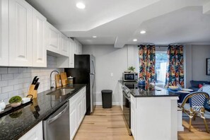 Cozinha moderna com armários brancos, geladeira preta e bancada de madeira.