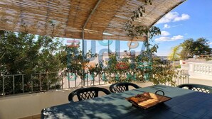 Un área de estar al aire libre con una mesa y sillas, un dosel de bambú y vistas a un edificio con murales coloridos.