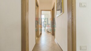 Un pasillo con puertas de madera, suelo de baldosas y un cuadro enmarcado en la pared.