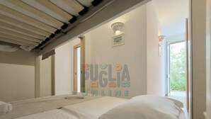 Un dormitorio con dos camas, ventilador de techo, una ventana y una lámpara de pared.
