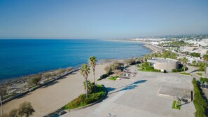 Vista aérea de una zona costera con playa, estacionamiento y edificios.