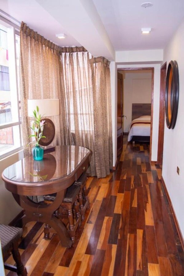 Ein Hotelzimmer mit Holzboden, einem Esstisch mit Stühlen, einem Bett und einem großen Spiegel an der Wand.