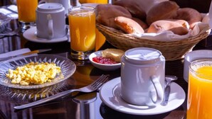 Desayuno con huevos revueltos, jugo de naranja, cruasanes y una taza de café.