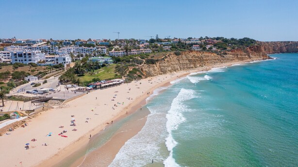 A coastal town with a sandy beach, clear blue sea, and residential buildings along the cliff. - Stunning Modern Apartment [122] (Lagos)