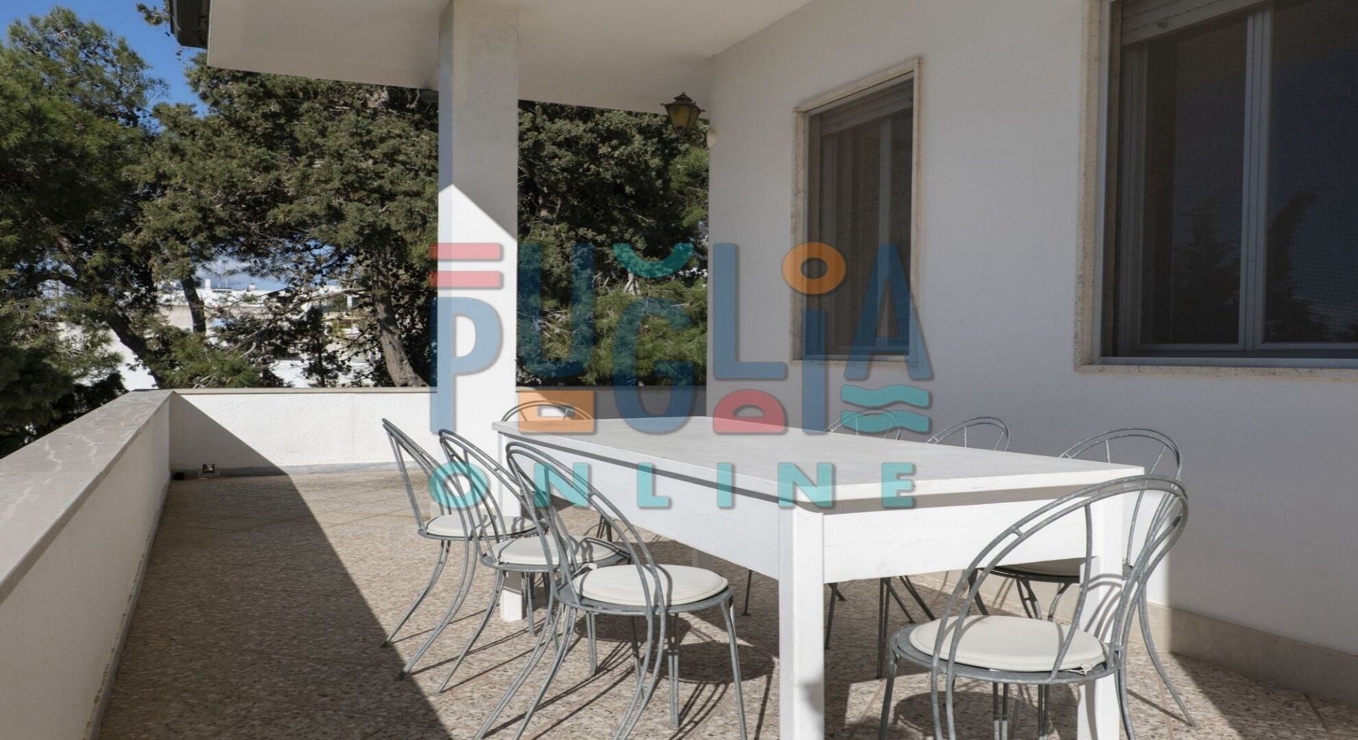 A white table with four chairs on an outdoor patio.