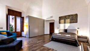 Un dormitorio amplio con una cama grande, un sofá y vistas al exterior.