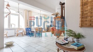 A spacious room with a dining area, a large window, and a woven wall hanging. - Villa Pisa 1 in Torre Vado (torre vado)