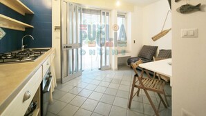 A kitchen with a gas stove, a sink, and a dining area with a table and chairs. - Vacation Home Lu Ientu Torre Vado (Torre vado)