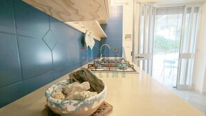 A modern kitchen with a blue backsplash, a gas stove, and a bowl of snacks on the counter. - Vacation Home Lu Ientu Torre Vado (Torre vado)
