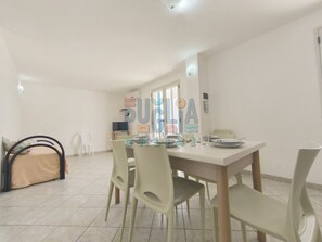 A dining area with a table, chairs, and a television. - Turquoise Apartment Torre Vado (Torre Vado)