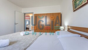 Una camera d'albergo con un letto, un armadio in legno, una porta e un quadro incorniciato al muro.