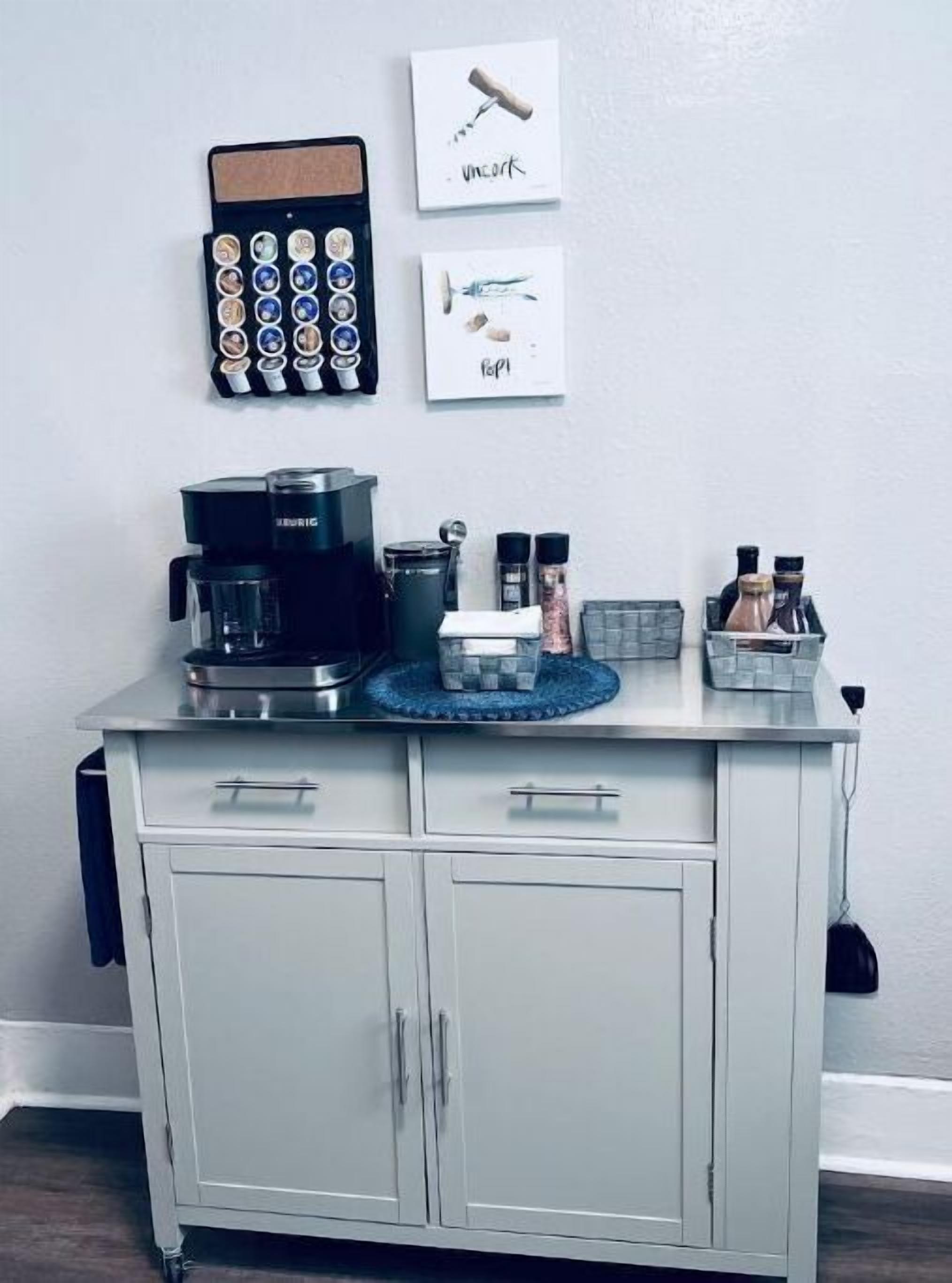 Une cuisine équipée d’une machine à café, d’un porte-épices et d’un tableau d’affichage en liège où sont disposés des grains de café et un bouchon de liège.