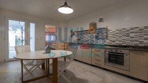 Moderni keittiö, jossa on ruokailutila, suuri ikkuna, sisäänrakennettu uuni ja laatoitettu seinäosa työtason yläpuolella.