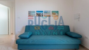 A teal sofa with a large wall decoration spelling "PUCLIA ONLINE" above it, featuring nautical-themed artwork. - Apartment Gioia 1 in Marina di Pescoluse (Torre Vado)