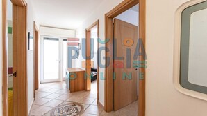 A hallway with wooden doors, a tiled floor, and a bench. - Villa Ilenia in Marina di Mancaversa (Taviano)