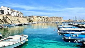 A marina with boats docked, a historic building, and a clear blue sky. - Villa Lungomare Galilei on the waterfront in Gallipoli (Gallipoli)
