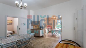 A spacious living area with a dining table, chairs, a sofa, and a kitchen area. - Villa Lungomare Galilei on the waterfront in Gallipoli (Gallipoli)