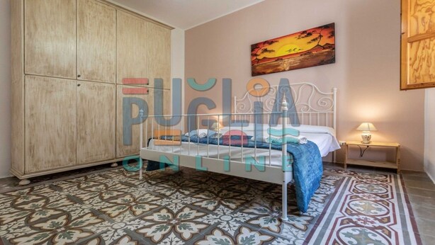 A bedroom with a bed, a wardrobe, a painting, and a patterned floor. - Villa Lungomare Galilei on the waterfront in Gallipoli (Gallipoli)