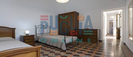 A bedroom with a bed, a nightstand, a dresser, and a wardrobe.