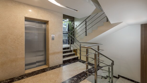 A modern elevator, a staircase with metal railings, and a marble floor. - Treebo Hiland Suites (Bengaluru)
