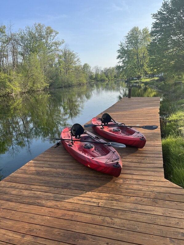 Two red kayaks on a wooden dock by a calm river with trees on both sides. - NEW! Rivers Edge Cabin (Waterloo)