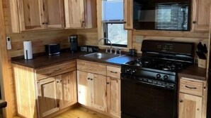A wooden kitchen with a stove, sink, and cabinets.
