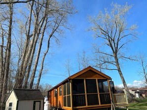 A cabin with a pitched roof and large windows, surrounded by trees. - NEW! Rivers Edge Cabin (Waterloo)