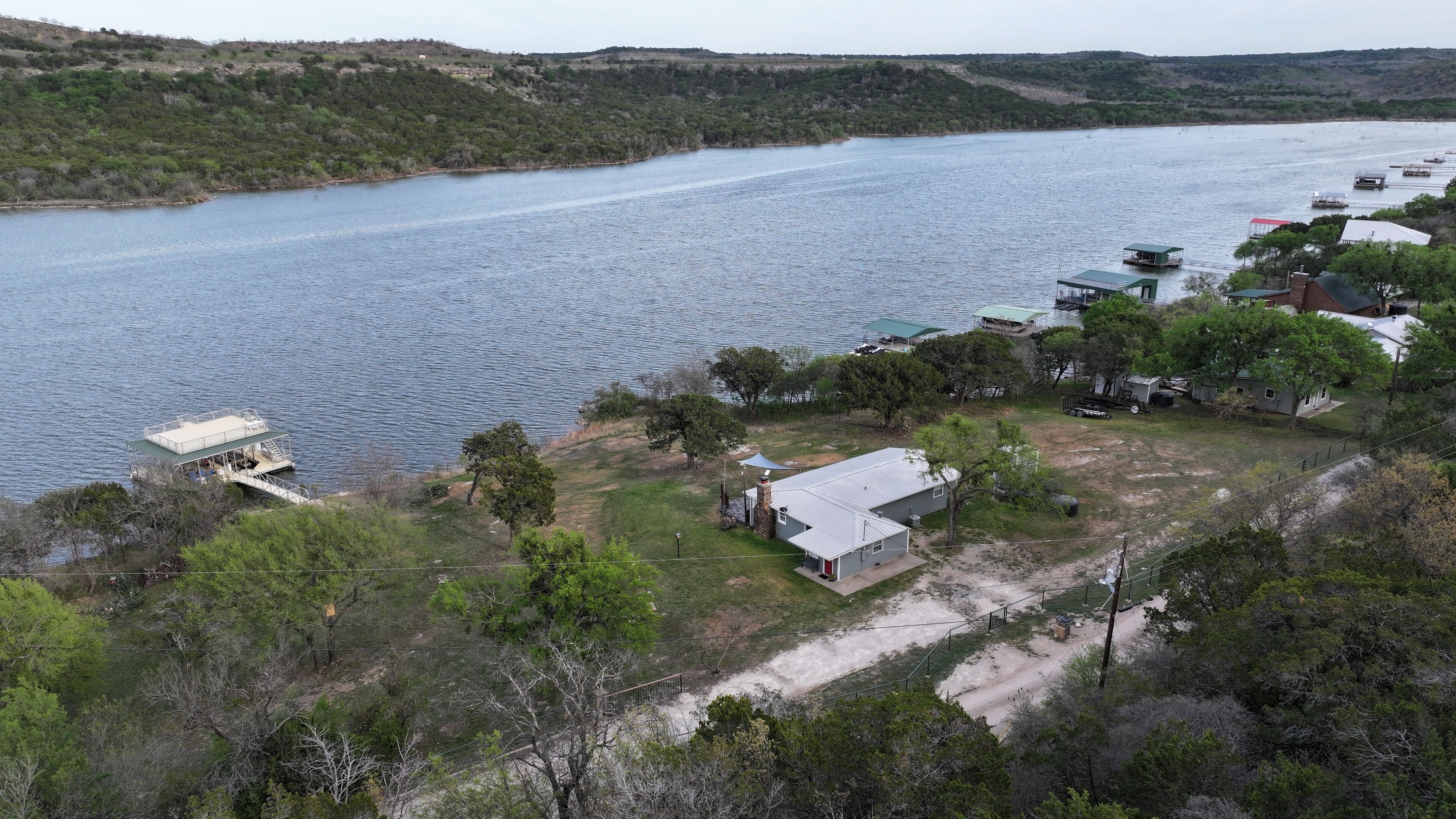 Une propriété au bord du lac, comprenant un quai, une petite maison et un bateau.