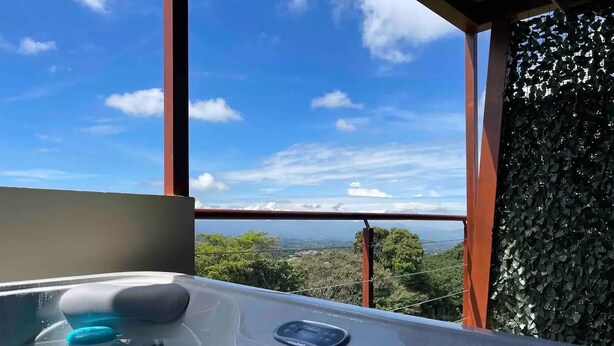 A hot tub with a view of a mountainous landscape through a window. - Loft & Jacuzzi Great View VG Poás (Poás)