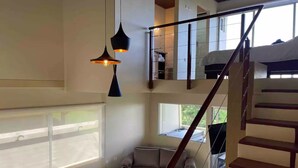 A spacious living area with a high ceiling, a staircase, and large windows providing natural light. - Loft & Jacuzzi Great View VG Poás (Poás)