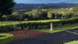 A landscaped area with a paved path, a stone border, and a view of distant mountains and a town. - Loft & Jacuzzi Great View VG Poás (Poás)